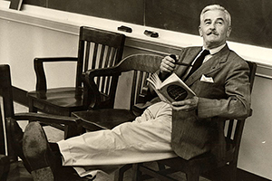 William Faulkner teaching at University of Virginia, with his feet up, reading a book