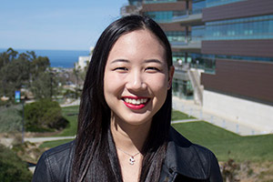 Young Japanese woman smiling with a view of campus and the ocean behind her