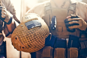 Marine relaxing while in full gear, holding helmet.