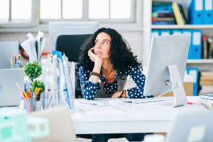 Woman with long, dark curly hair stares off into space, distracted