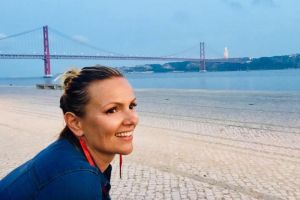 Pretty woman smiling at someone out of frame next to a beach in the San Francisco area