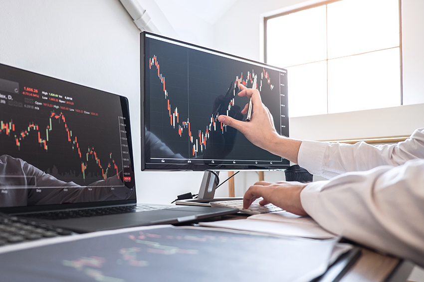 Business person's arms seen on desk, with hands manipulating data chart on computer screen