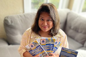 Woman holding a stack of books and smiling at the camera.