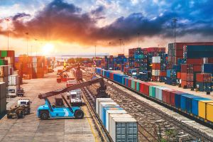 Very colorful shipping yard with a lovely sunrise behind it.