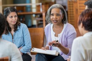 Older woman giving advice to a circle of people. Image represents the Substance Abuse Counselor program