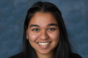 Young woman with dark hair and eyes smiles enthusiastically