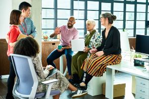 A diverse group of people sitting in a brightly lit office, having a meeting.