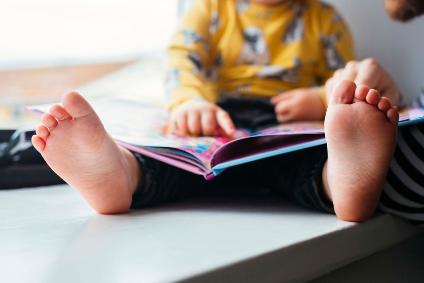 Child reading a colorful children's book with an adult