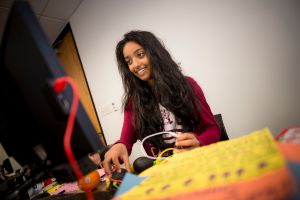 Young woman experiments with electronics and a computer