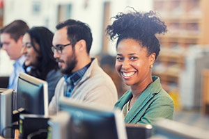 Attractive young black woman smiling in front of a computer screen.