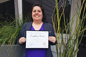 Woman smiling and holding an award certificate.